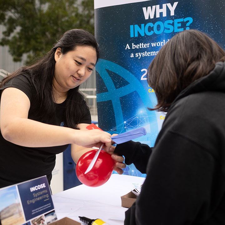 adult helping student with balloon activity related to STEM